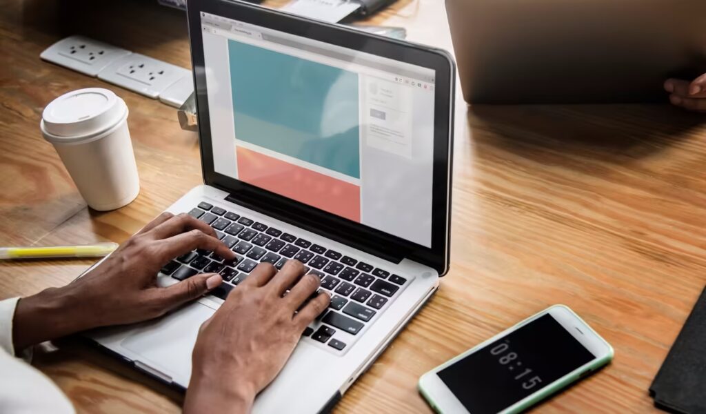 Notebook aberto exibindo um site em construção sobre uma mesa de trabalho